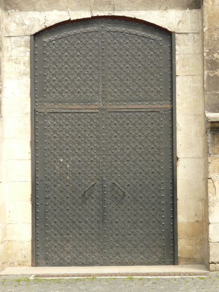 Heavy dark grey metal doors with arching top and star and circle pattern engraved in surface.
